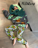 Load image into Gallery viewer, Child wearing Yoda-themed pajamas with a green personalized PillowScript pillow  spelling 'Cole" covering part of his face while laying on a wooden floor.

